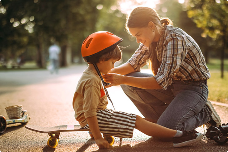 BPI Reforma Vida PPR 2060. Imagem de uma mãe sorridente, num parque, a colocar o capacete a uma criança.