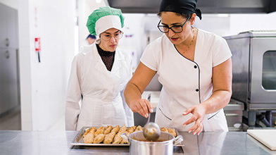 Duas mulheres na cozinha a cozinhar.