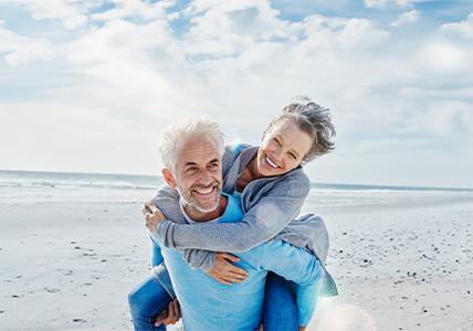 Casal na praia sorridente com o complemento de reforma proporcionado pela solução de poupança BPI Casa 65.