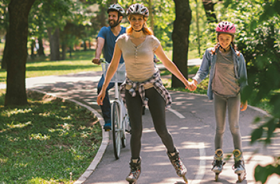 Imagem de família feliz a andar de bicicleta e patins no parque