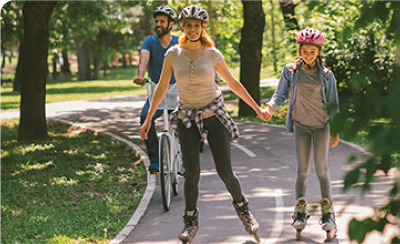 Imagem de família feliz a andar de patins e bicicleta  no parque