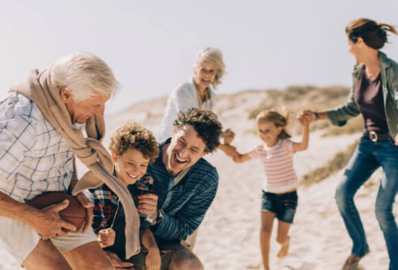 Familia jugando en la playa, con su futuro planeado. Seguro de Capitalización BPI.