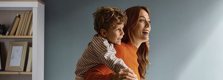 BPI Reforma Vida PPR. Imagem de uma mãe sorridente, em casa, com uma criança sorridente às cavalitas.
